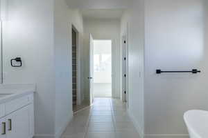 Bathroom with vanity, light tile patterned floors, a spacious closet, and a freestanding bath