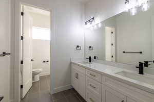 Bathroom featuring double vanity and dark tile patterned flooring