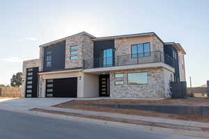 Contemporary home featuring stone siding, stucco siding, concrete driveway, and a balcony