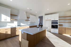 Kitchen featuring open shelves, dark wood-style flooring, an island with sink, stainless steel appliances, and recessed lighting