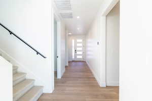 Hallway with stairs, light wood-style flooring, and recessed lighting