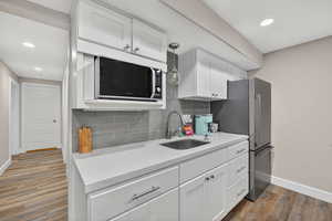 Kitchen with white cabinetry, light stone countertops, recessed lighting, tasteful backsplash, and freestanding refrigerator