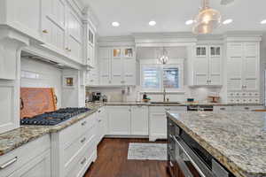 Kitchen with glass insert cabinets, decorative light fixtures, decorative backsplash, white cabinetry, and recessed lighting