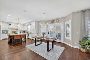 Dining space with a chandelier and dark wood-style floors