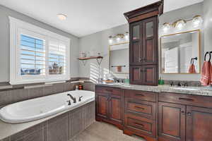 Full bath featuring double vanity and a garden tub