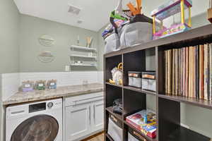 Laundry room with washer / clothes dryer and light wood-style flooring
