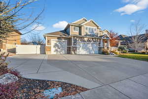 Craftsman-style house featuring a gate, board and batten siding, stone siding, concrete driveway, and a garage