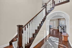 Stairway with arched walkways, hardwood / wood-style flooring, and a high ceiling