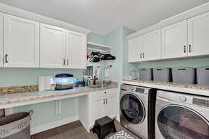 Laundry area with dark tile patterned floors, separate washer and dryer, and cabinet space
