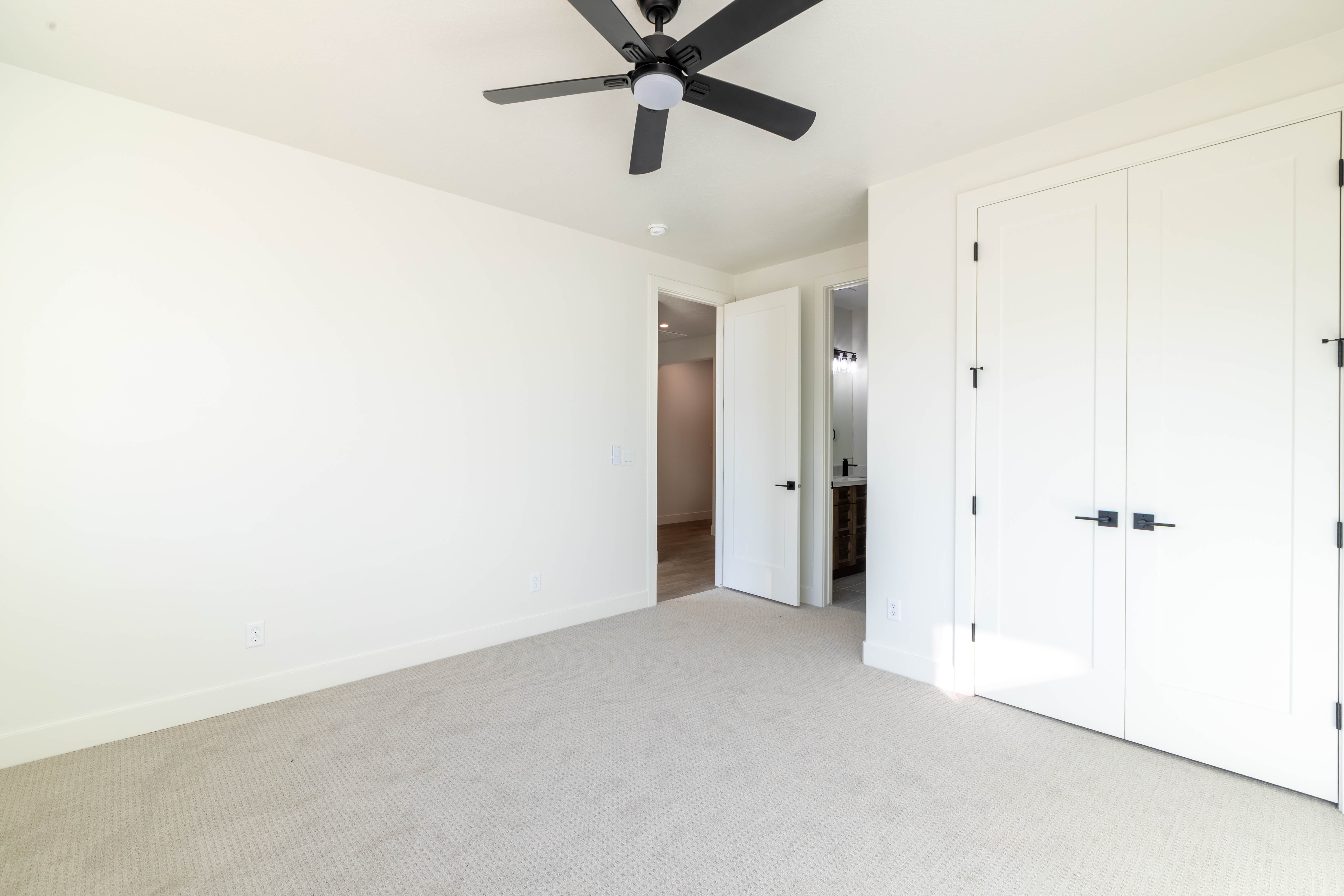 Unfurnished bedroom featuring carpet, ensuite bathroom, a closet, and a ceiling fan