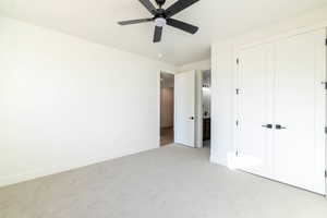 Unfurnished bedroom featuring carpet, ensuite bathroom, a closet, and a ceiling fan