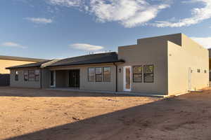 Back of house featuring a patio, stucco siding, and roof with shingles