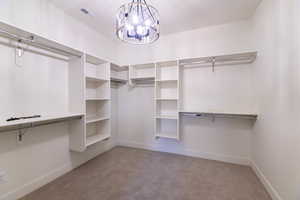 Spacious closet with light colored carpet and a chandelier