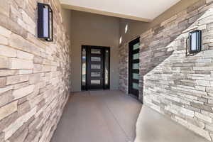 Doorway to property featuring stone siding and a patio area