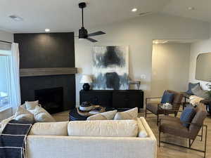 Living room with a tile fireplace, ceiling fan, vaulted ceiling, wood finished floors, and recessed lighting