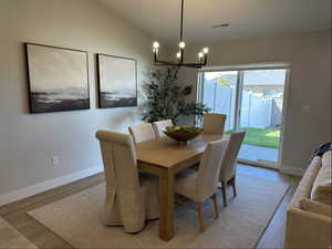 Dining area featuring light wood finished floors, vaulted ceiling, and a chandelier