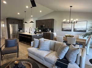 Living room with light wood-style floors, lofted ceiling, a chandelier, and recessed lighting