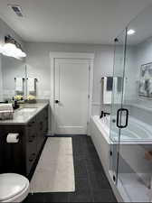 Bathroom with a garden tub, vanity, and a stall shower