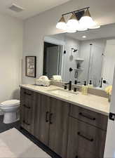 Bathroom with a stall shower, vanity, and dark tile patterned flooring
