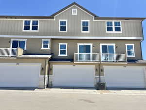 Rear view of property featuring a balcony, stucco siding, and a garage