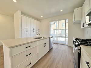 Kitchen with stainless steel appliances, white cabinets, a kitchen island with sink, and recessed lighting