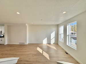 Unfurnished living room featuring recessed lighting, a textured ceiling, and light wood finished floors