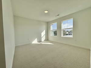 Empty room with carpet floors and a textured ceiling