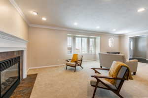 Sitting room with crown molding, a fireplace, carpet floors, and recessed lighting