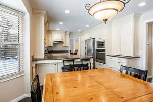 Kitchen featuring stainless steel appliances, recessed lighting, a kitchen breakfast bar, dark stone counters, and pendant lighting