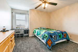 Bedroom with dark carpet and a ceiling fan