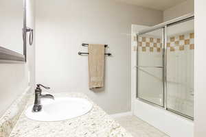 Full bathroom with vanity, enclosed tub / shower combo, and light floors