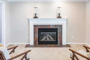 Detailed view of a tiled fireplace, carpet, and ornamental molding