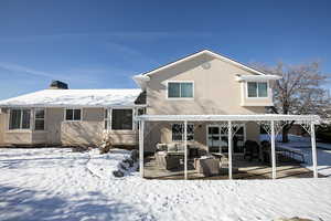 Snow covered property featuring a patio area, an outdoor living space, stucco siding, and a chimney