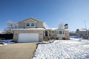 View of front of house featuring brick siding, a garage, concrete driveway, and a chimney
