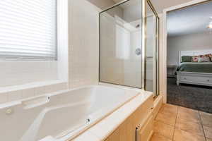 Full bath featuring a bath, a shower stall, light carpet, ensuite bathroom, and light tile patterned flooring