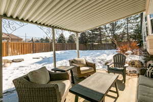 Snow covered patio with a fenced backyard and a patio