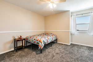 Bedroom with dark colored carpet and a ceiling fan