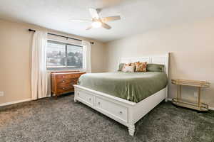 Bedroom featuring dark colored carpet, ceiling fan, and a textured ceiling