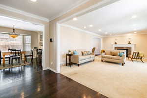 Carpeted living area featuring hardwood / wood-style floors, a fireplace, crown molding, and recessed lighting