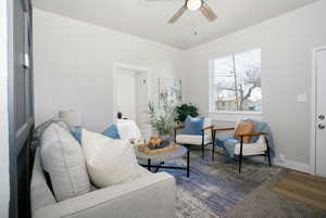 Living area with ceiling fan and baseboards
