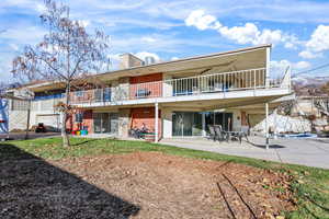 Back of property featuring brick siding, a patio, a balcony, and a chimney