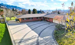 View of front of house with brick siding, driveway, a mountain view, and a garage