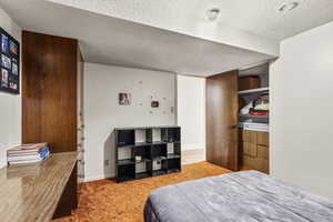 Bedroom with a textured ceiling and light carpet
