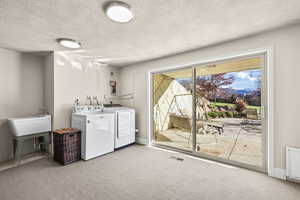 Laundry room featuring a textured ceiling, washer and clothes dryer, and carpet floors