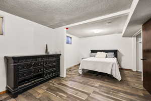 Bedroom with a textured ceiling and dark wood-style flooring