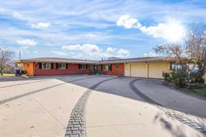 Ranch-style house featuring driveway, an attached garage, and brick siding