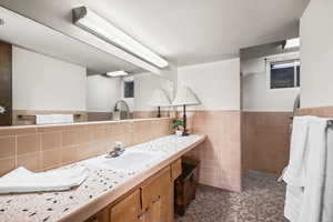 Bathroom featuring vanity, wainscoting, and tile walls