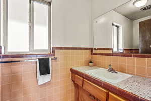 Bathroom featuring vanity, wainscoting, and tile walls