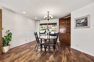 Dining area with a chandelier, dark wood-style floors, and recessed lighting
