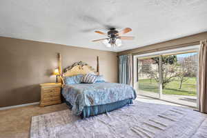 Master Carpeted bedroom with access to outside, a textured ceiling, and ceiling fan